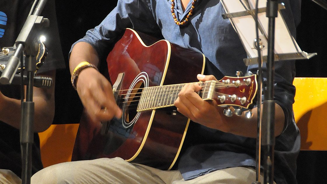 Een jongen speelt gitaar en zingt.